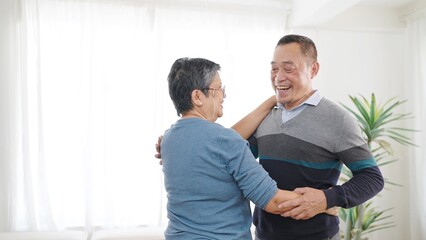 Happy asian senior couple enjoy dancing together in living room at home. Sweet elderly couple enjoy love moment. Retirement lifestyle of asian couple senior concept