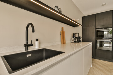 a modern kitchen with black and white appliances on the countertop, along with an island sink in the center