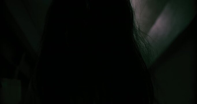 Horror scene of a mysterious Scary closeup Asian ghost woman creepy have hair covering the face looking to camera with background dark scene movie at night, festival Halloween concept