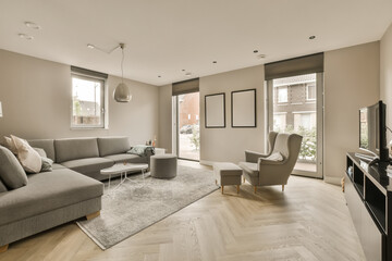 a living room with wood flooring and gray couches in front of the sofa is an area for tvs to sit on
