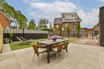 a backyard area with a table, chairs and some flowers on the grass in the patio is surrounded by brick walls