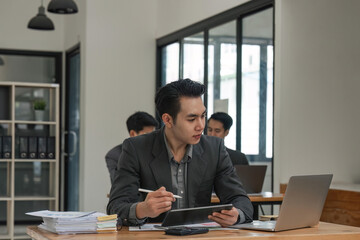 Fototapeta premium business man sitting in office and working on laptop and tablet