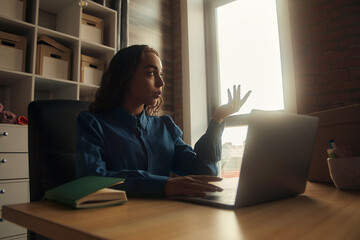 Side view. Young business woman is sitting at the table and. On the table is a laptop, smartphone and. On the computer screen graphs and charts. The student is studying online. Blogger. entrepreneur