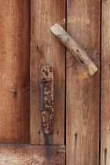 Old rusty handle and latch on vintage wooden door.