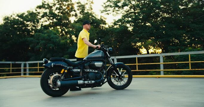 Male instructor at a driving school sets the motorcycle to the correct place. Driving instructor in yellow t-shirt
