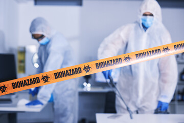 Hazard, tape and people in danger working with toxic, biology or team disinfect dangerous bacteria...