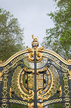 Ornate golden royal coat of arms on decorative wrought iron gate at Buckingham Palace, London, United Kingdom