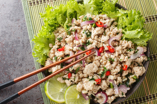 Larp or Laab gai or larb gai spicy salad breast chicken with herb closeup on the plate on the table. Horizontal top view from above