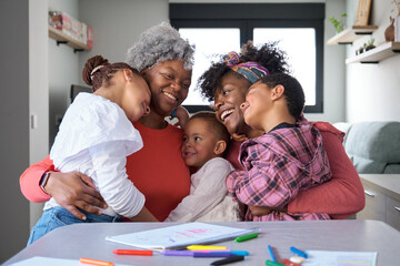 Portrait of a happy african horizontal extended family hugging and laughing at home. - obrazy, fototapety, plakaty