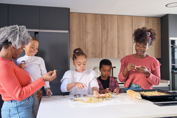 African family cutting cookie shapes in a cookie dough in the kitchen. Horizontal extended family.