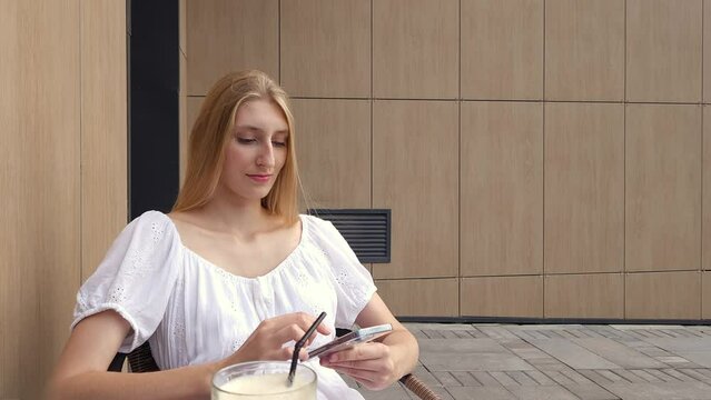 Young woman using smartphone and drinking raf coffee