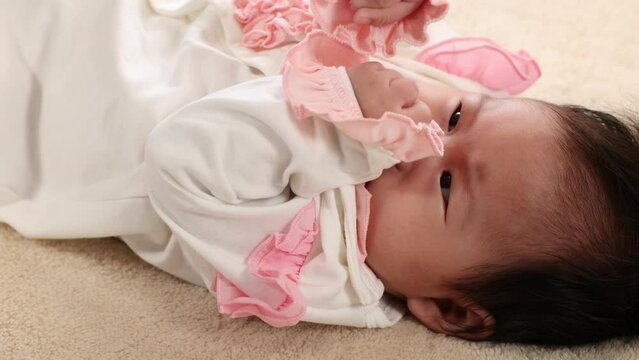 Curiosity Asian newborn crying with tear in eye feel uncomfortable or sick on bed, infant feel tempered or hungry, closeup unhappy face of toddler, upset toddler need cudding embrace from mother