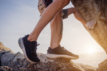 Young couple climbs to the top in the mountains near the ocean