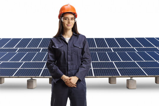 Young female technician with a helmet and goggles posing in front of photovoltaics