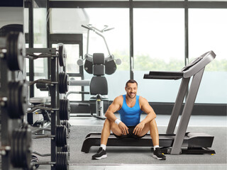 Fototapeta na wymiar Smiling young man sitting on a treadmill