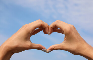 shape of an HEART made with the hands of the girl with nail polish