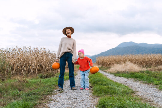 Mother and daughter with pumpkins in pumpkin patch.