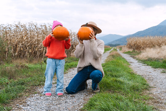 Mother and daughter with pumpkins in pumpkin patch.