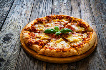 Pizza Serrano with cooked ham, mozzarella cheese and vegetables on wooden table

