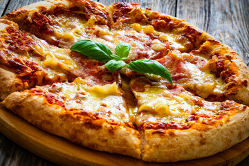 Pizza Serrano with cooked ham, mozzarella cheese and vegetables on wooden table
