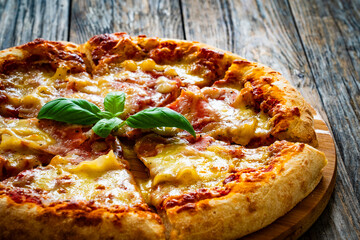 Pizza Serrano with cooked ham, mozzarella cheese and vegetables on wooden table
