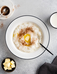 Rice porridge with milk, butter and cinnamon powder in white ceramic plate. Delicious homemade...