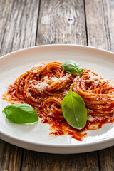Spaghetti marinara - noodles with tomato sauce, parmesan cheese and basil leaves served on wooden table
