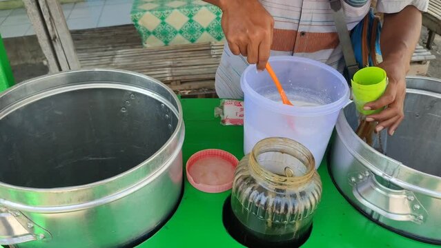 An ice cendol vendor makes a delicious drink on a hot afternoon