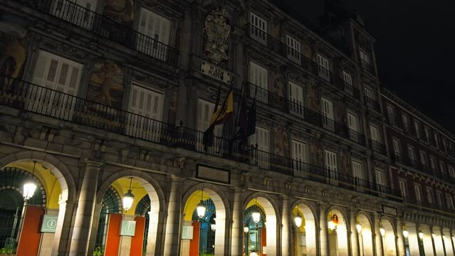 Tourists visiting Plaza Mayor Historical landmark at night in Madrid, Spain. People walk in Plaza Mayor Square with Cafes and restaurants and the statue of Philip III