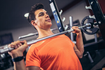 Young handsome man doing exercises in gym
