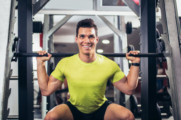 Young handsome man doing exercises in gym