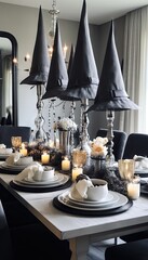 a black and white halloween table setting with candles, napkins, pumpkins, witches hats and other...