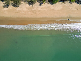 Top down drone shot of the beach with white waves crashing, Cairns