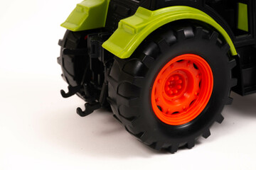 A green, orange and grey toy  farm tractor   isolated on a white background