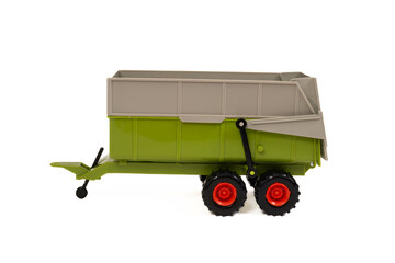 A green, orange, and grey toy farming tractor  trailer isolated on a white background