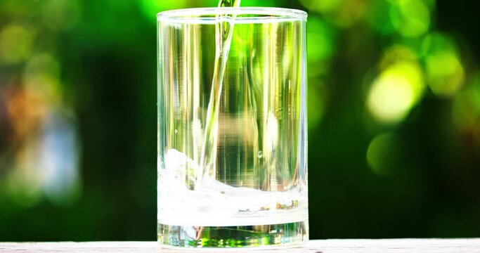 Close-up and slow motion pouring water into transparent glass of water. Pouring Liquid Freshness: A Transparent Glass of Water, Bubbles, and Refreshing Drink. 