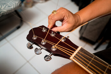 Young musician changing strings on a classical guitar in a guitar shop