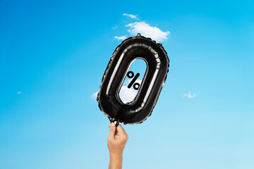 Hand holding black zero percentage balloon on blue sky for special sale offer of shopping...