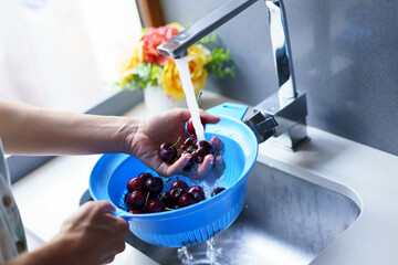 Anonymous woman washing cherries in sink