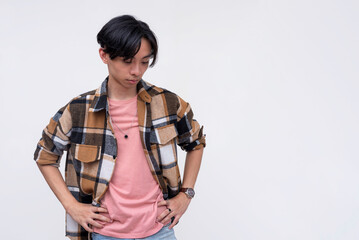 Fototapeta premium A sad young asian man unsure of what to do, looking down. Isolated on a white background.