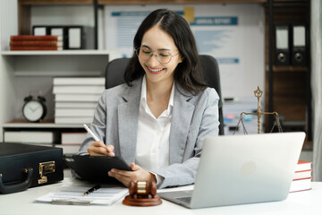 Justice and law concept. Female judge in a courtroom with the gavel working with digital tablet computer docking keyboard on wood table.