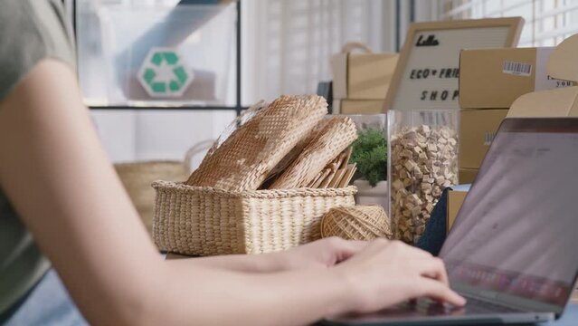 Save the planet earth Eco friendly box store in net zero waste shop asian seller digital retail working at home office. ESG Small SME owner woman asia people typing chat laptop on AI chatGPT chatbot.