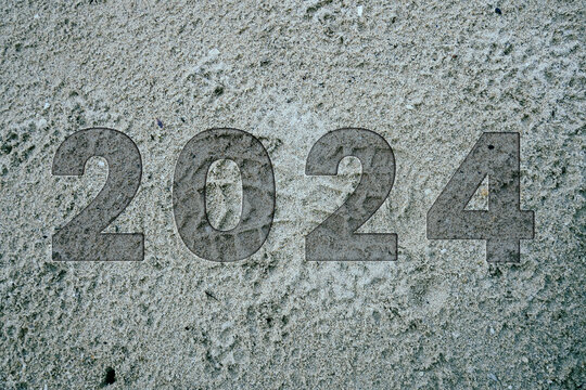 2023 in the sand and 2024 engraved in wooden cubes on a beautiful beach. The concept of moving the new year from 2023 to 2024.