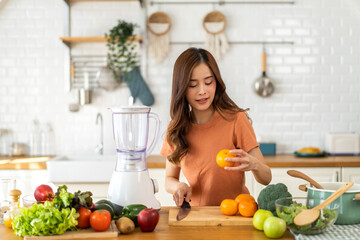 Portrait of beauty healthy asian woman making orange fruit smoothie with blender.girl preparing...
