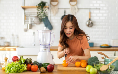 Portrait of beauty healthy asian woman making orange fruit smoothie with blender.girl preparing cooking detox cleanse with fresh orange juice in kitchen at home.health, vitamin c, diet, healthy drink