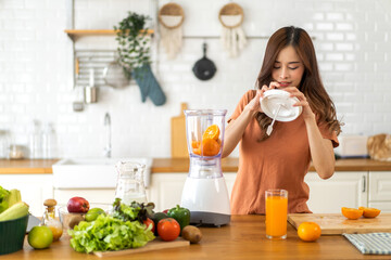 Portrait of beauty healthy asian woman making orange fruit smoothie with blender.girl preparing cooking detox cleanse with fresh orange juice in kitchen at home.health, vitamin c, diet, healthy drink