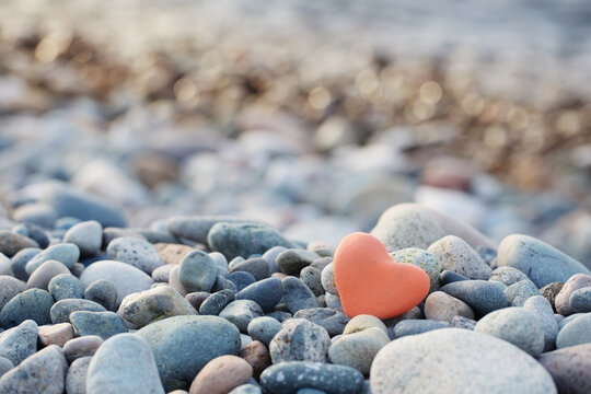 red stone in  shape of heart on  beach by  sea