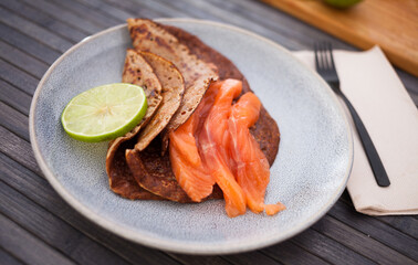 Salted salmon fillet with buckwheat pancakes and lime