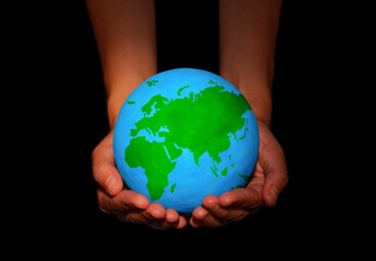 Hands Holding a Globe with Lush Green Continents on Black
