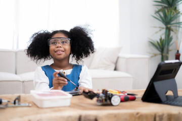 African American kid looking her parent while playing with electronic robotic follow by video study...